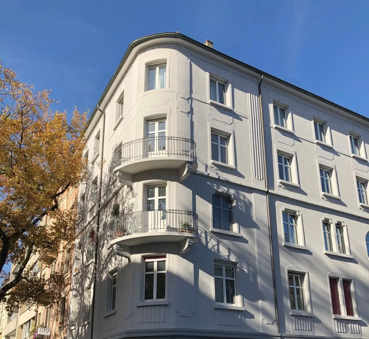 Dasselbe Eckhaus mit hellgrauer Fassade nach dem Neuanstrich